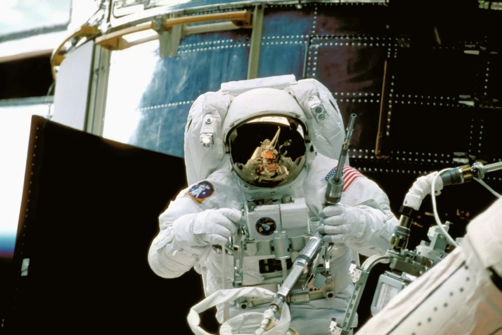 A NASA astronaut in front of a space station working on the Hubble Space Telescope.